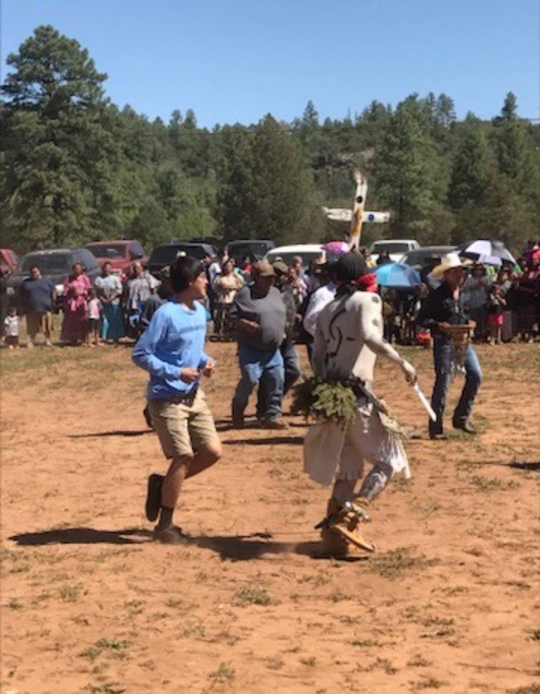 man and traditional dancer dancing with trees in the background